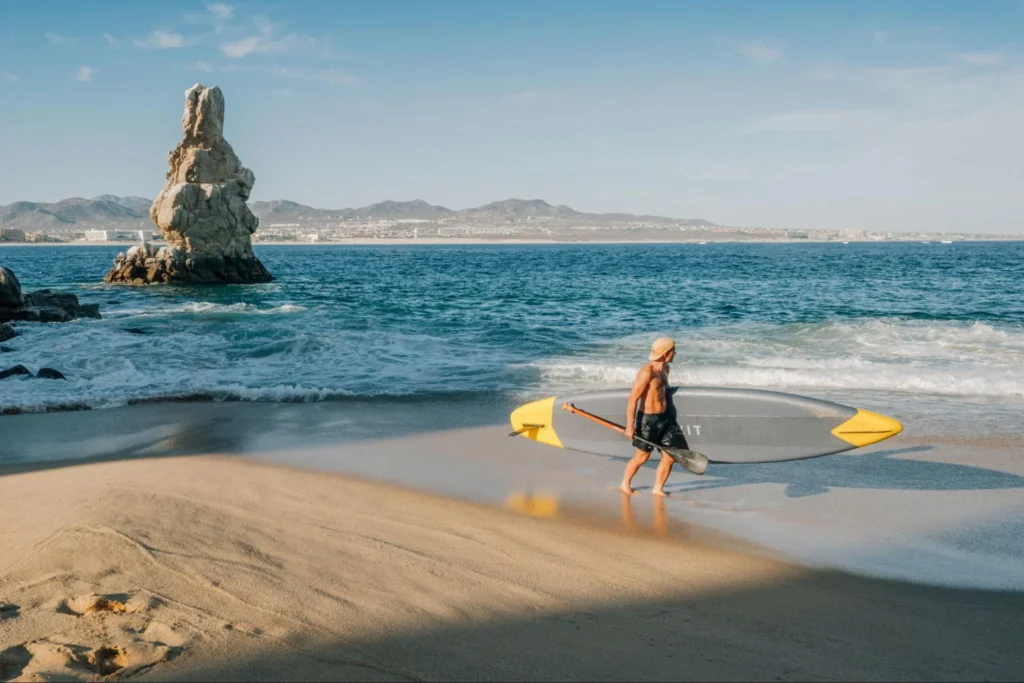 A man about to surf while walking in the shore.