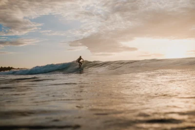 Woman surfing in the beach while sunser arise.
